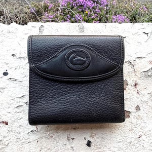 May include: A white ceramic mug with a black handle and the text "But First, Coffee" in a bold, black font. The mug is set against a blurred background, highlighting its clean design.