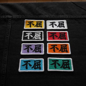 K&ouml;nnte beinhalten: Sechs gestickte Patches mit den chinesischen Schriftzeichen f&uuml;r "nicht m&uuml;de" in Schwarz auf verschiedenen farbigen Hintergr&uuml;nden: Gelb, Wei&szlig;, Lila, Orange, Blau und Gr&uuml;n.