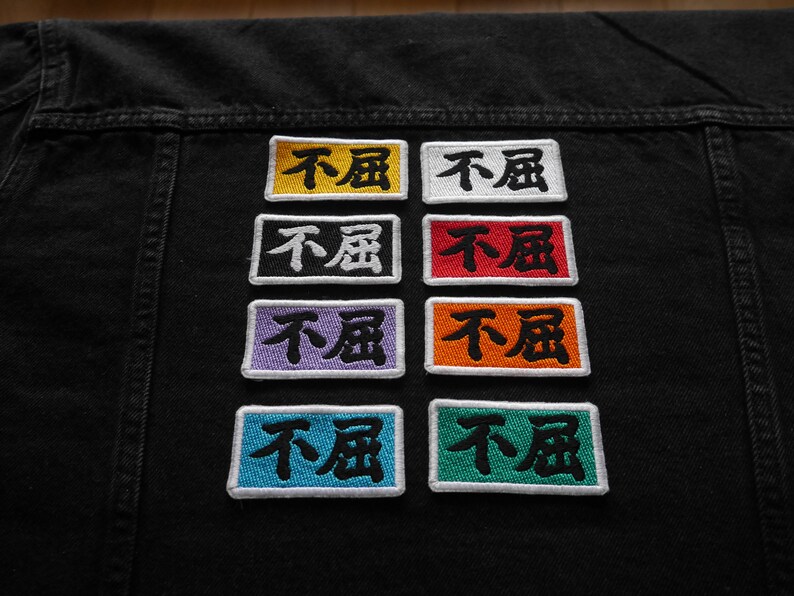 K&ouml;nnte beinhalten: Sechs gestickte Patches mit den chinesischen Schriftzeichen f&uuml;r "nicht m&uuml;de" in Schwarz auf verschiedenen farbigen Hintergr&uuml;nden: Gelb, Wei&szlig;, Lila, Orange, Blau und Gr&uuml;n.