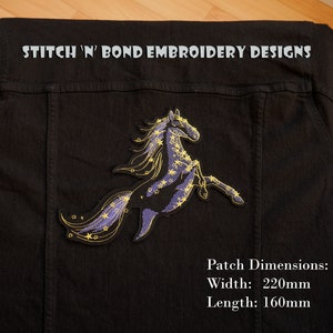 Può includere: Una giacca di jeans nera con una toppa ricamata in viola e oro di un cavallo con criniera e coda stellate. La toppa misura 220 mm di larghezza e 160 mm di lunghezza. "STITCH 'N' BOND EMBROIDERY DESIGNS" è stampato sulla giacca.