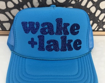 May include: A bright blue trucker hat with a blue glitter design that says "wake + lake".