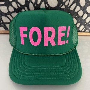 May include: Green trucker hat with a pink "FORE!" embroidered on the front.