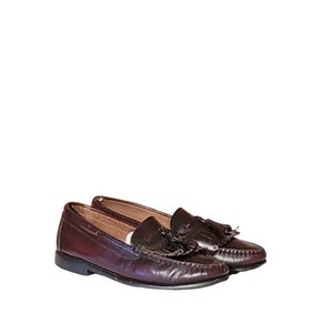 May include: A pair of brown leather tassel loafers. The loafers have a pointed toe and a low heel.