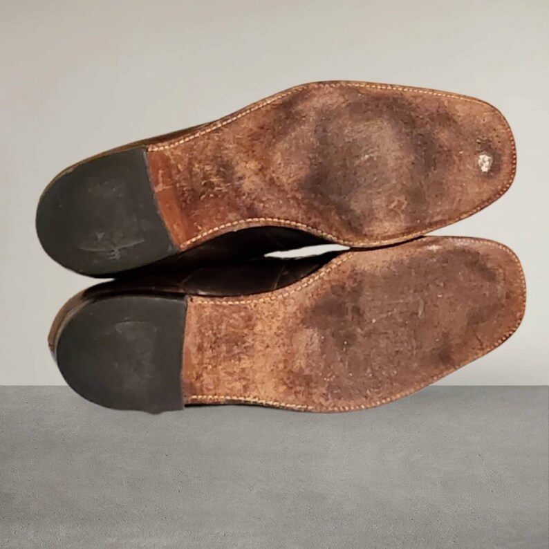 Puede incluir: Primer plano de las suelas de cuero marr&oacute;n de un par de zapatos. Las suelas est&aacute;n gastadas y tienen un patr&oacute;n texturizado.