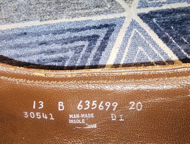 Puede incluir: Primer plano de una plantilla de zapato de cuero marr&oacute;n con el texto "13 B 635699 20 30541 MAN-MADE INSOLE 51" impreso en ella.