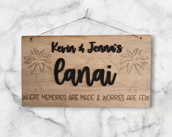 Può includere: Un cartello di legno con il testo "Kevin & Jenna's Lanai" e la frase "Where memories are made & worries are few". Il cartello è decorato con palme.