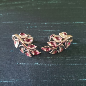 Puede incluir: Un par de pendientes de plata en forma de hoja. Los pendientes están hechos de metal y tienen un diseño delicado y femenino.