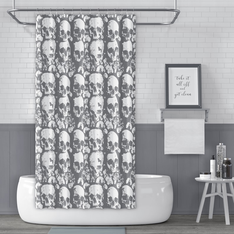 May include: A grey shower curtain with a white skull pattern. The text "Take it all off and get clean" is on a framed sign above a white bathtub.