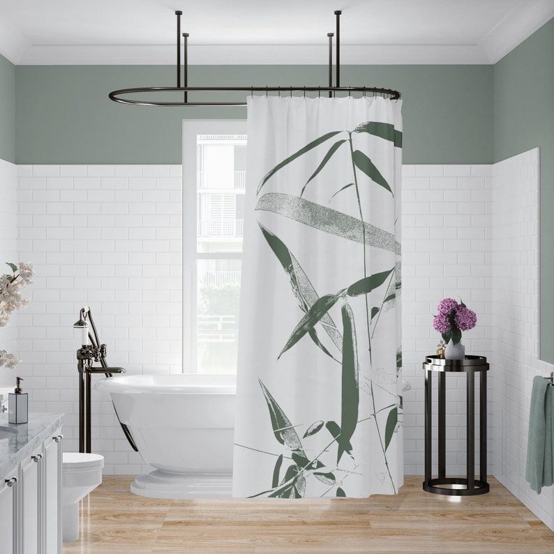 Puede incluir: Cortina de ducha blanca con un dise&ntilde;o de hojas verdes. La cortina est&aacute; colgada en un ba&ntilde;o con paredes de azulejos blancos tipo metro y una ba&ntilde;era blanca.