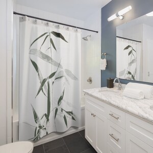 Puede incluir: Cortina de ducha blanca con un estampado de bamb&uacute; negro y verde. La cortina de ducha est&aacute; colgada en un ba&ntilde;o con un tocador blanco y una encimera de m&aacute;rmol.