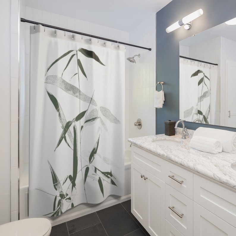 Puede incluir: Cortina de ducha blanca con un estampado de bamb&uacute; negro y verde. La cortina de ducha est&aacute; colgada en un ba&ntilde;o con un tocador blanco y una encimera de m&aacute;rmol.