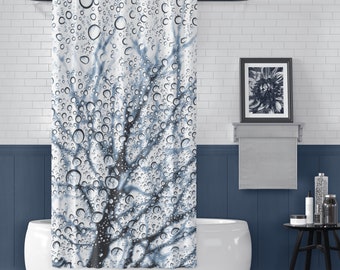 May include: A white shower curtain featuring a blue tree silhouette design. The tree is obscured by water droplets, creating a blurred effect.