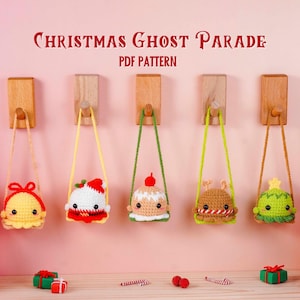 Puede incluir: Cinco adornos de fantasmas navideños de ganchillo, cada uno con un diseño único, cuelgan de clavijas de madera. Los adornos son amarillos, blancos, beige, marrones y verdes. El texto "Christmas Ghost Parade PDF Pattern" está en la parte superior.