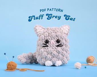 Könnte beinhalten: PDF-Muster für eine gehäkelte graue Katze mit weißen Pfoten und einer rosa Nase. Die Katze sitzt auf einer blauen Oberfläche mit Garn und Nadeln.