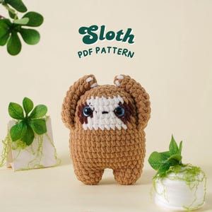 Puede incluir: Un juguete de perezoso tejido a ganchillo con cuerpo marrón, cara blanca y ojos azules. La imagen incluye el texto "Sloth PDF Pattern" en una fuente verde retro. Plantas decorativas están colocadas alrededor del perezoso.