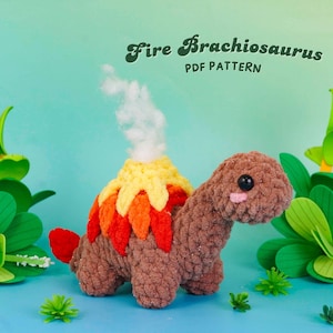 May include: A handmade crochet Brachiosaurus dinosaur with a volcano on its back. The volcano is yellow, orange, and red, with white smoke. The dinosaur is brown with a pink cheek. The text "Fire Brachiosaurus PDF Pattern" is above the dinosaur.