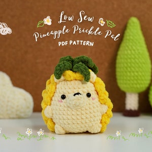 May include: A crocheted pineapple-shaped plush toy with a green top and yellow body. The toy is sitting on a white surface with green grass and white flowers drawn around it. The text "Low Sew Pineapple Prickle Pal PDF Pattern" is written above the toy.