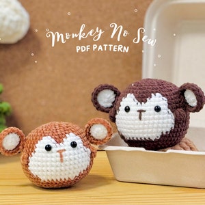 May include: Two crocheted monkey toys, one brown and one orange, with white faces and black eyes. The brown monkey is in a white takeout container. The text "Monkey No Sew PDF Pattern" is on a brown background.