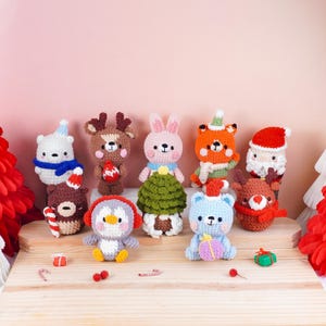 May include: A collection of handmade crochet Christmas ornaments. The ornaments include a polar bear, reindeer, bunny, fox, Santa, bear, penguin, and a blue bear. Each ornament is uniquely designed with festive colors and details, perfect for holiday decor.