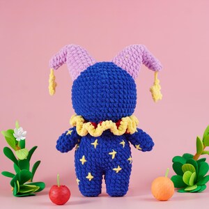 May include: A handmade blue plush doll with a jester hat and collar. The doll has yellow star accents and a ruffled yellow collar. The jester hat is lavender with yellow star-shaped tassels. The doll is approximately 8 inches tall.