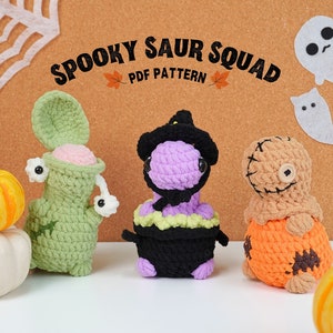 Peut inclure: Trois dinosaures en crochet sur le thème d'Halloween. Le premier est vert avec l'intérieur rose et des yeux globuleux. Le deuxième est violet avec un chapeau de sorcière noir et un chaudron noir. Le troisième est brun avec des détails cousus et une citrouille.
