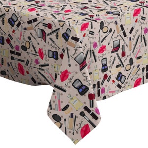May include: A beige tablecloth with a repeating pattern of makeup items, including lipstick, eyeshadow palettes, nail polish, perfume bottles, and makeup brushes. The pattern is in shades of pink, red, black, and brown.
