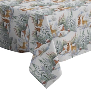 May include: White tablecloth with a winter woodland scene featuring brown deer, small houses, and evergreen trees. The background is a light blue with white snow.