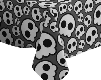 May include: Black and white tablecloth with a skull pattern. The skulls are in various sizes and are outlined in white. The background is a dark gray.