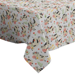 Könnte beinhalten: Weißer Tischdeckenstoff mit einem sich wiederholenden Muster aus niedlichen Comic-Kühen mit schwarzen Flecken und rosa Nasen. Die Kühe sind von grünen Blättern und kleinen roten Blumen umgeben. Der Text "Cute cows" wiederholt sich im gesamten Muster.