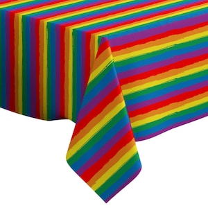 May include: A rectangular tablecloth with a vibrant rainbow stripe design. The stripes are in red, orange, yellow, green, blue, and purple. The fabric has a textured appearance, and the tablecloth is folded over a table.