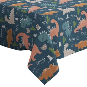May include: A blue tablecloth with a repeating pattern of colorful dinosaurs and the word "ROAR!" printed on it.