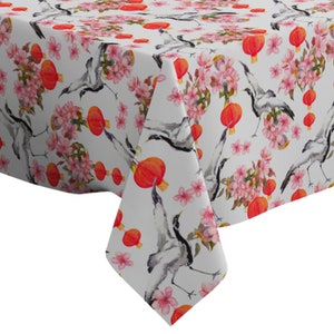 Könnte beinhalten: Weißer Tischdeckenstoff mit einem sich wiederholenden Muster aus roten Laternen, rosa Blüten und grauen Kranichen.