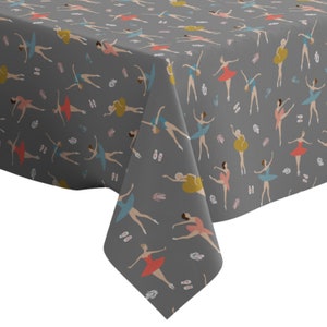May include: A grey tablecloth featuring a repeating pattern of colourful ballerinas in various poses. The ballerinas are wearing pink, blue, yellow and red tutus. The background is a dark grey colour.