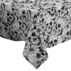 Puede incluir: Mantel de mesa blanco y negro con un patrón de calaveras y flores. El mantel está hecho de una tela suave y duradera y es perfecto para agregar un toque de estilo gótico a su comedor.