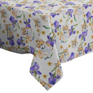 Peut inclure: Nappe blanche avec un motif répété d'illustrations à l'aquarelle de corgis et de fleurs d'iris violettes.