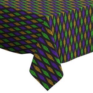 May include: A black tablecloth with a repeating pattern of gold, green, and purple diamonds. The tablecloth is made of a textured fabric that resembles glitter.
