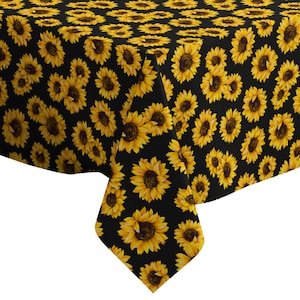 Op de afbeelding: Zwarte tafelkleed met een herhalend patroon van gele zonnebloemen.