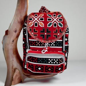 Peut inclure: Sac à dos rouge avec un motif géométrique et une petite poche avant. Le sac à dos est fait d'un tissu tissé et a une fermeture à glissière.