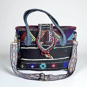 May include: A black and multi-colored woven tote bag with a patterned shoulder strap and handles. The bag features geometric designs in red, blue, and green, with a decorative flap and beaded accents. The bag has a detachable shoulder strap.