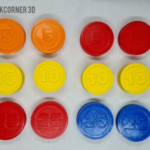 Può includere: Una collezione di dodici gettoni circolari in plastica disposti su tre file. La fila superiore presenta due gettoni arancioni con il numero 5 e due gettoni rossi con il numero 5. La fila centrale ha quattro gettoni gialli con il numero 10. La fila inferiore contiene due gettoni rossi con il numero 25 e due gettoni blu con il numero 25.