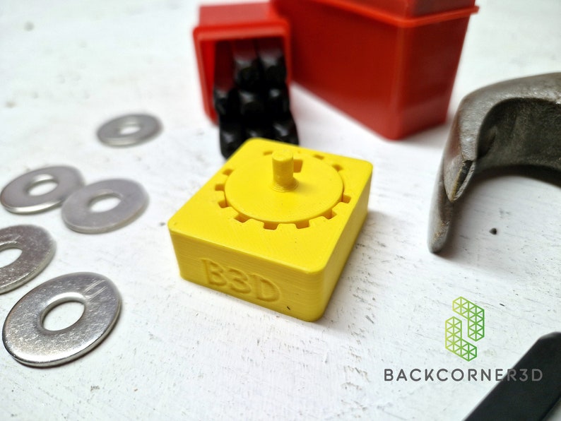Puede incluir: Un engranaje amarillo impreso en 3D con una peque&ntilde;a perilla en la parte superior. El engranaje tiene las letras "B3D" impresas en el lateral.