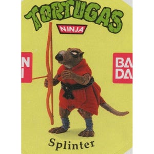 Op de afbeelding: Splinter, de ratten-sensei uit Teenage Mutant Ninja Turtles, houdt een boog en pijl vast. Hij draagt een rode robe en een zwarte riem. De afbeelding is van een vintage verzamelkaart.