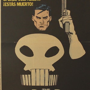 May include: Comic book poster featuring The Punisher. The image shows a skull, a man's face, and a hand holding a gun against a black background. Text at the top reads "SI ERES CULPABLE... ¡ESTÁS MUERTO!" and "THE PUNISHER" at the bottom.