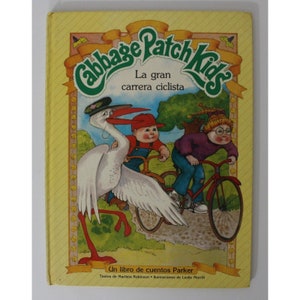Könnte beinhalten: Ein gelber Buchumschlag mit dem Titel "Cabbage Patch Kids" in grünen Buchstaben. Das Buch handelt von einem großen Radrennen und zeigt Illustrationen von drei Cabbage Patch Kids, die Fahrrad fahren. Der Text auf dem Umschlag lautet "La gran carrera ciclista" und "Un libro de cuentos Parker".