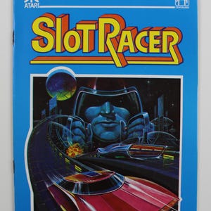 Könnte beinhalten: Eine blaue Atari-Spielkassette mit dem Titel "Slot Racer" in gelben und roten Buchstaben. Die Vorderseite der Kassette zeigt eine futuristische Stadtlandschaft mit einem roten Rennwagen, der durch die Stadt rast.