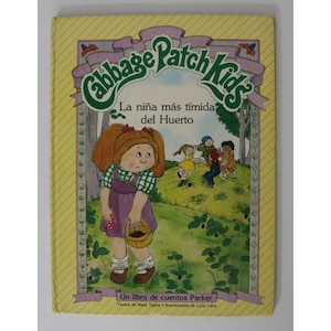 Könnte beinhalten: Ein gelber Buchumschlag mit dem Titel "Cabbage Patch Kids" in einem grün-violetten Banner. Das Buch zeigt eine Comic-Illustration eines Mädchens mit roten Haaren und einem violetten Kleid, das einen Korb mit Beeren hält. Der Text unter der Illustration lautet "La niña más tímida del Huerto" und "Un libro de cuentos Parker".