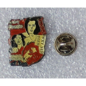 May include: A red, white, and black enamel pin featuring a portrait of a woman with the text "Sex Pistols" and "Why She Died" on the pin.