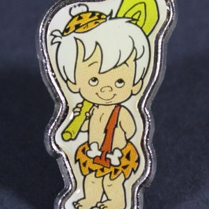 May include: A silver pin featuring a cartoon character with white hair, a yellow and orange hat, and a yellow club. The character is wearing a brown and orange loincloth with white bones.