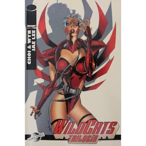May include: Comic book cover featuring a woman in a red and black costume with a spider-like design. The title "WildC.A.T.S. Trilogy" is printed in gold letters on the cover.