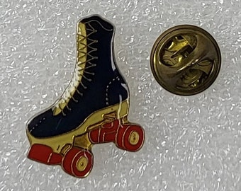Könnte beinhalten: Eine blaue und goldene Rollschuh-Anstecknadel mit roten Rollen. Die Nadel hat eine goldene Rückseite mit einer Sicherheitsnadel.